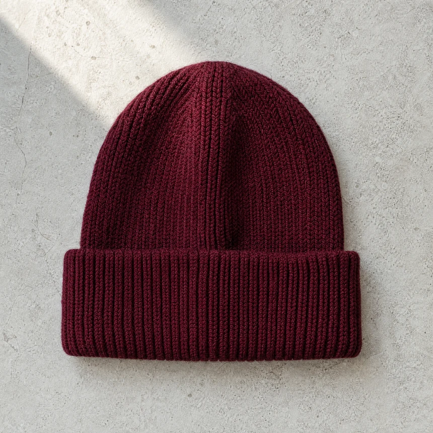 Gorro de punto con vuelta en color burdeos, sobre piedra clara