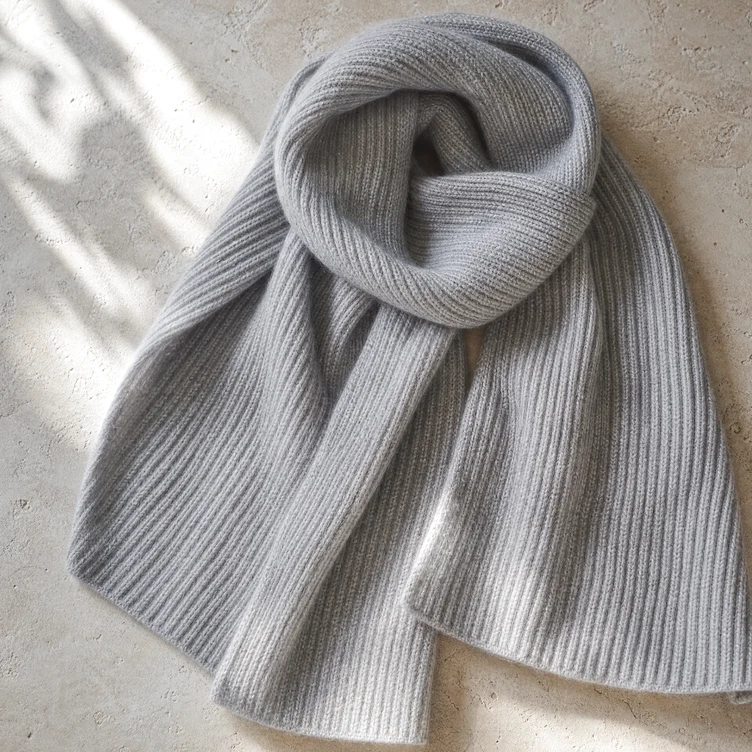 Bufanda de punto inglés en gris perla, muestra del punto de la manta, sobre piedra clara